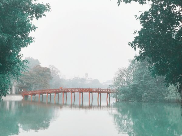 Puente rojo The Huc sobre el lago Hoan Kiem entre la bruma, Hanói
