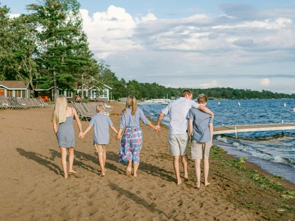 Familia con hijos adolescentes paseando por la playa de un lago