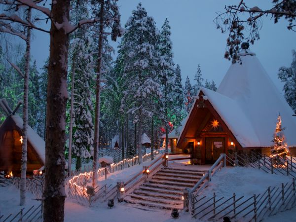 Cabañas nevadas iluminadas con luces de Navidad en el bosque de Rovaniemi, Laponia, Finlandia