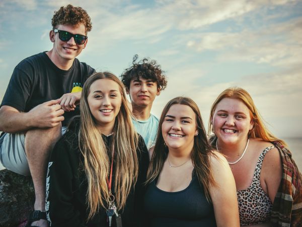 Grupo de adolescentes sonriendo al aire libre junto al mar