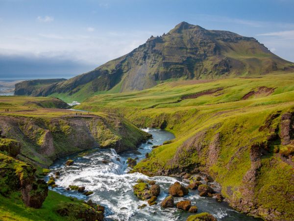 Río y cascadas entre colinas verdes en Islandia en verano