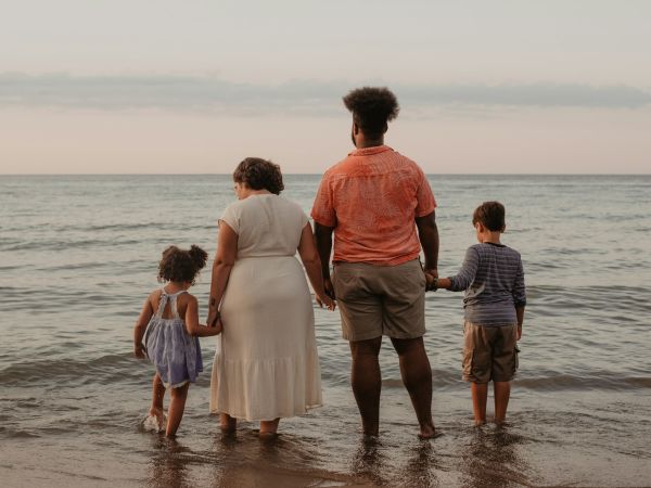 Padres con dos niños pequeños en la orilla del mar