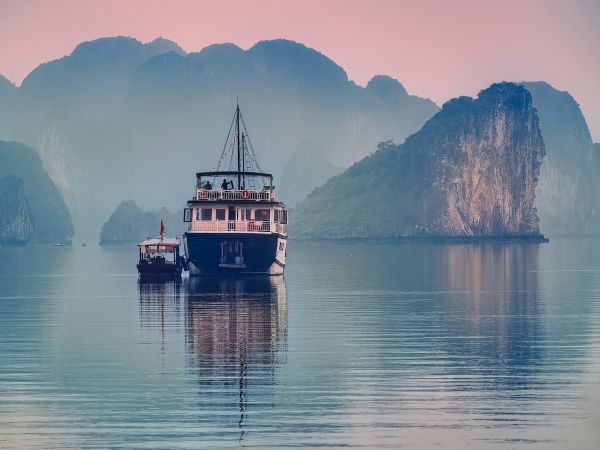 Junco tradicional navegando entre islotes kársticos con la bruma de la mañana, bahía de Ha Long