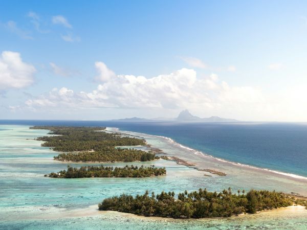 Vista aérea de los motus y la laguna de Taha'a con Bora Bora en el horizonte