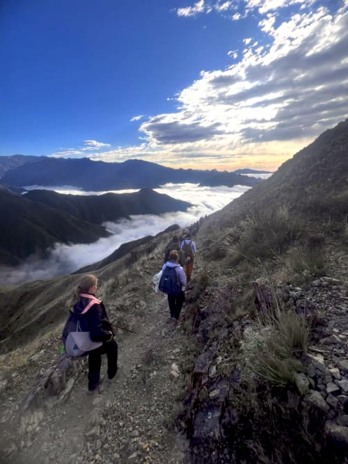 Grupo de personas haciendo trekking en montaña por encima de las nubes