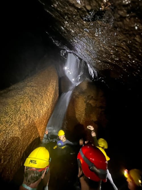 Grupo de trekking protegidos con cascos dentro de una cueva con agua