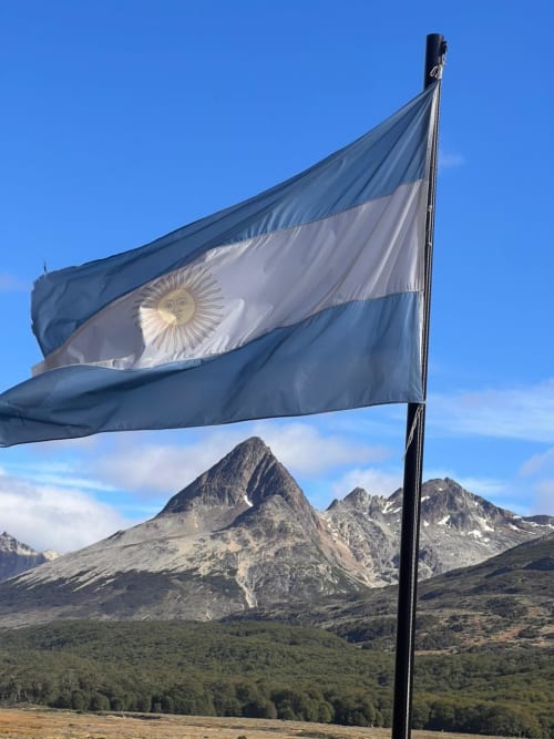 Bandera de la República Argentina flameando entre montañas en El Chaltén