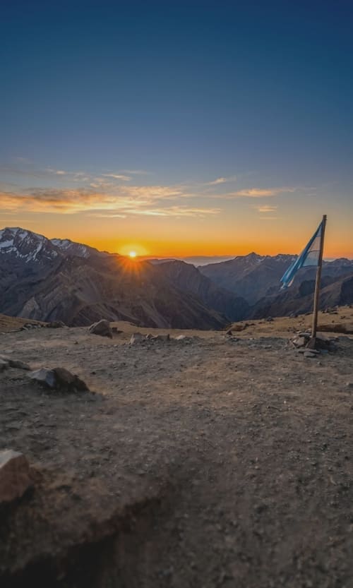 Bandera Argentina flameando frente al atardecer de la alta montaña