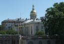 The gold dome of the New Jersey State House in Trenton rises above the capitol buildings under a clear blue sky