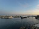 Malta's Grand Harbour at dusk seen from Valletta, with Fort St Angelo and Birgu on the left and a cargo ship heading into port
