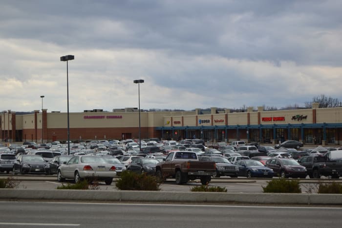Cars fill the parking lot in front of a row of stores at a shopping centre in Cranberry Township, Pennsylvania, under a heavy grey sky