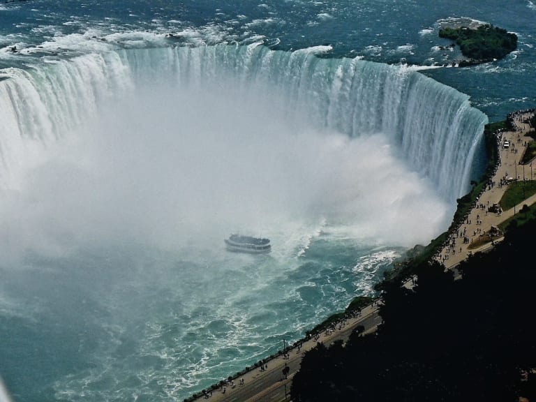 Aerial view of the Horseshoe Falls at Niagara, with a tour boat in the mist below and the Ontario shoreline on the right