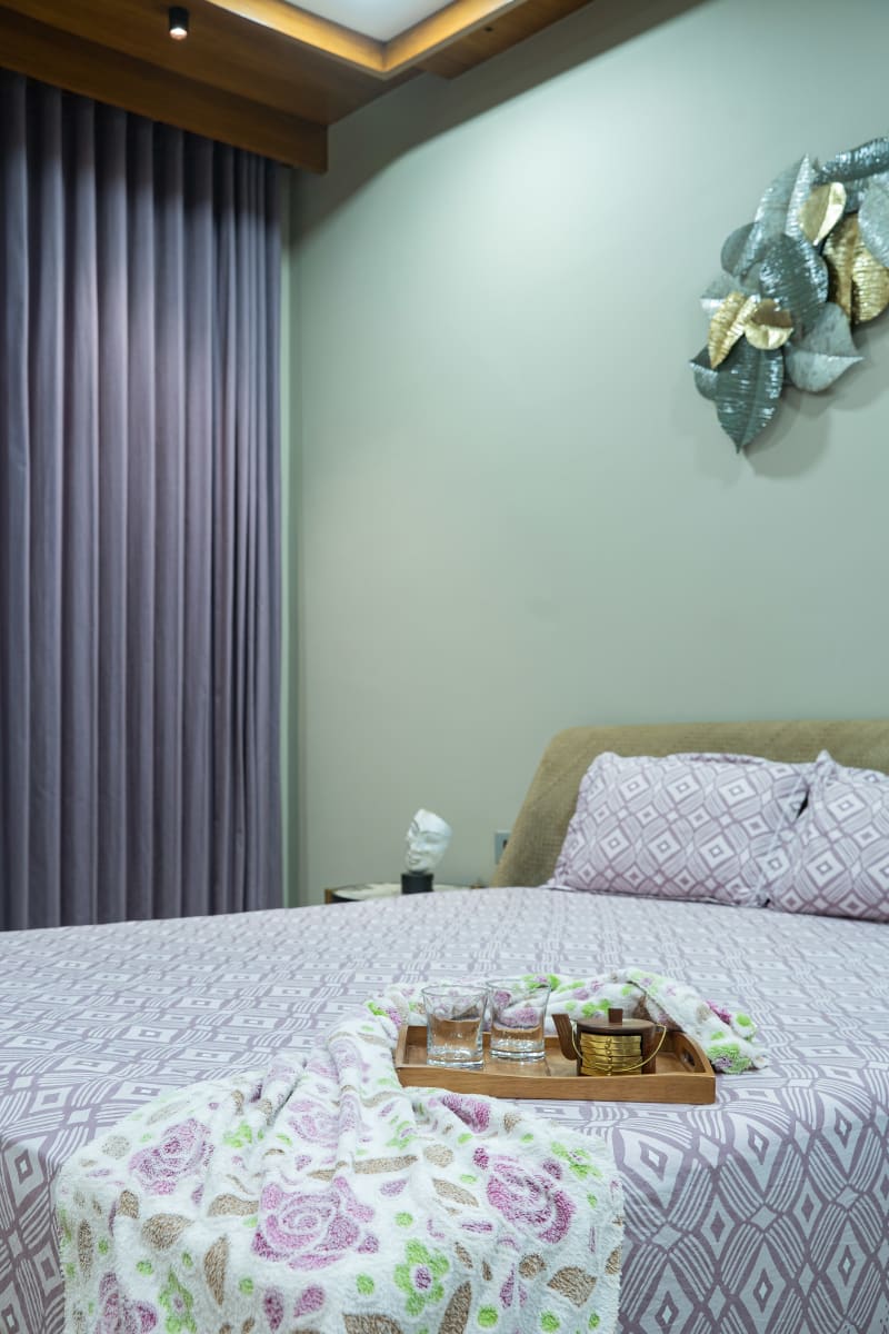 Bed with purple patterned sheet and wooden tray