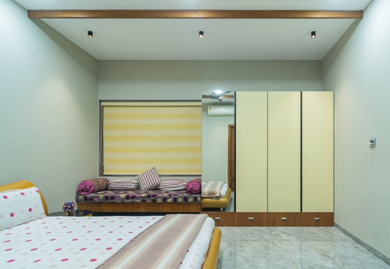 "Yellow-themed bedroom with wardrobe and mirror"