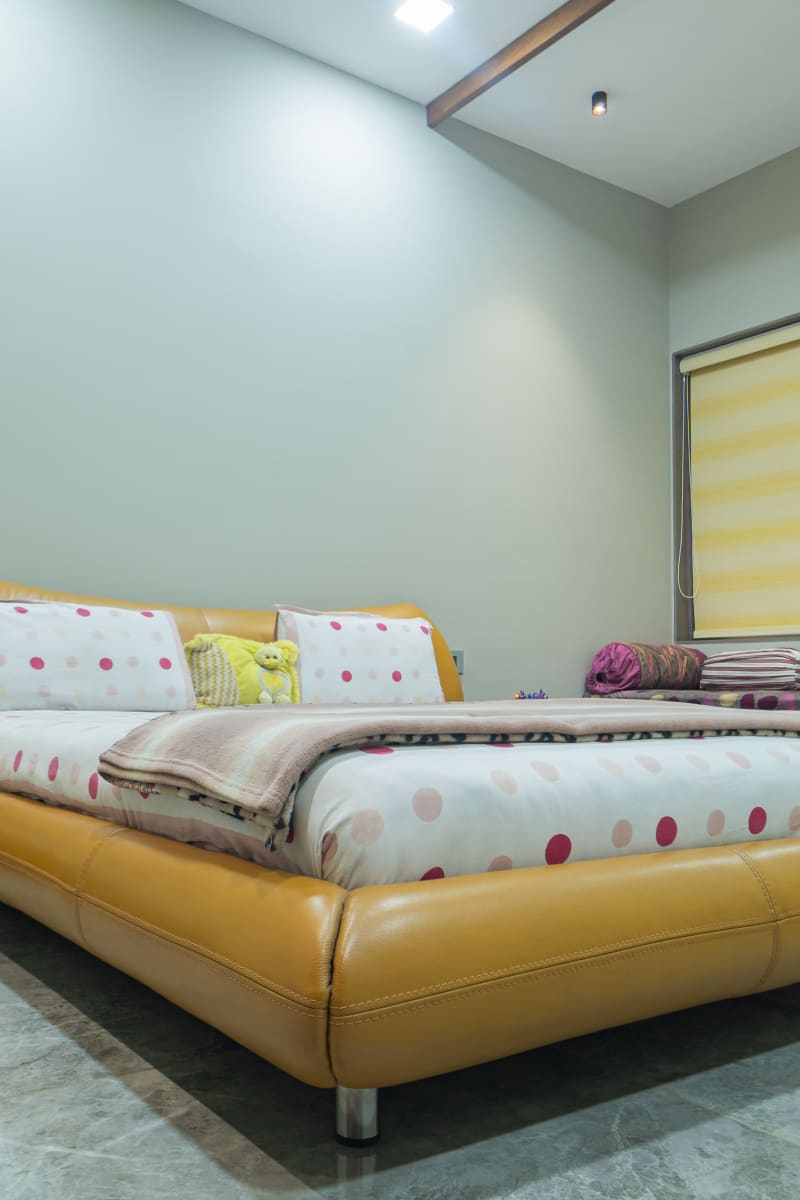 "Yellow leather bed frame with polka-dot bedding"