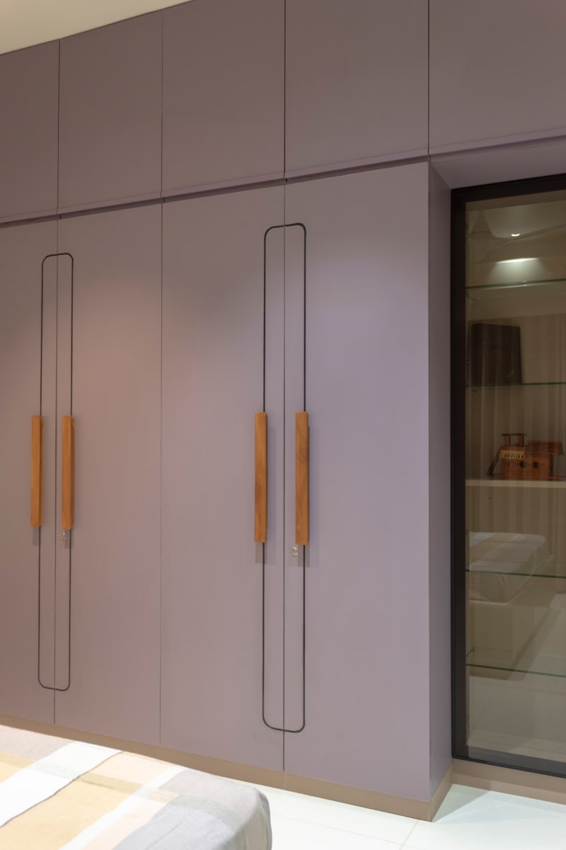 Purple wardrobe with wooden handles in bedroom