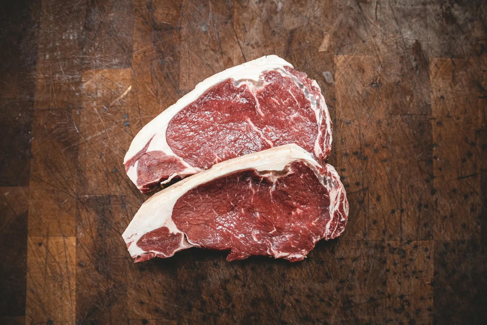 Raw red meat cuts on a butcher board