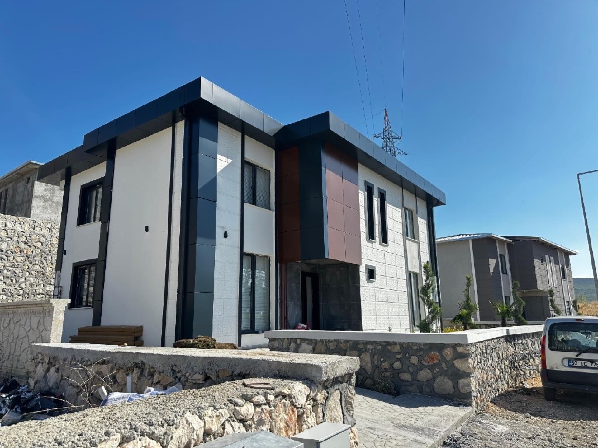 Modern müstakil konut dış cephe: beyaz sıva, antrasit panel ve ahşap görünüm — Tokat