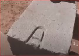 Close-up of a large andesite stone block at Puma Punku (Tiwanaku complex, Bolivia), showing a distinctive recessed T-shaped or dovetail groove (swallowtail cramp recess) cut into the surface, designed to hold poured metal clamps for securing blocks together.