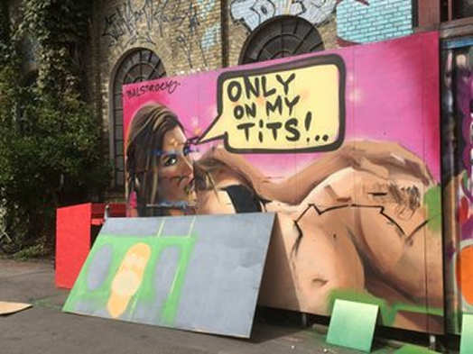 Provocative street art mural in Christiania, Copenhagen featuring a reclining female figure and bold graffiti-style lettering