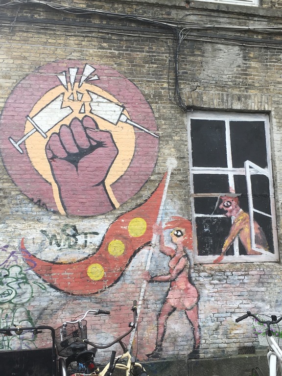 On the wall there is a hand drawn, clenched into a fist, with a broken syringe and needle in it