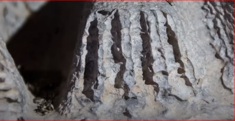 "Close-up detail of intricately carved parallel grooves and channels in the massive Inca stonework at Sacsayhuamán, Peru, showcasing the precision of ancient stone carving."