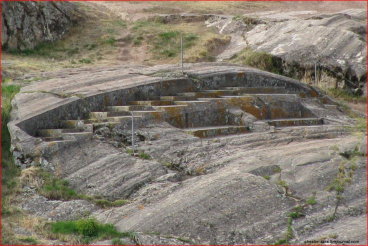 "Ancient Inca carved stone terraces and stepped structure built into the natural rock at Sacsayhuamán archaeological site near Cusco, Peru, showing intricate stonework covered with lichen and moss."