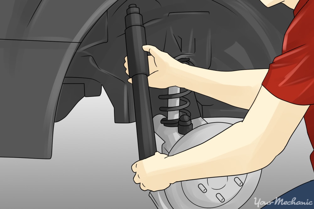 person fitting a new shock absorber onto a car