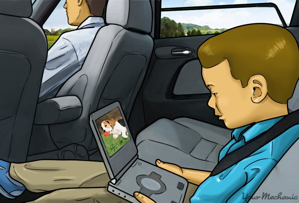 child sitting in back seat holding a dvd player