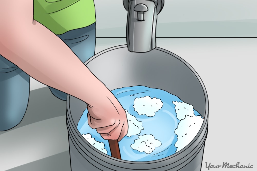 hand mixing soapy water in bucket