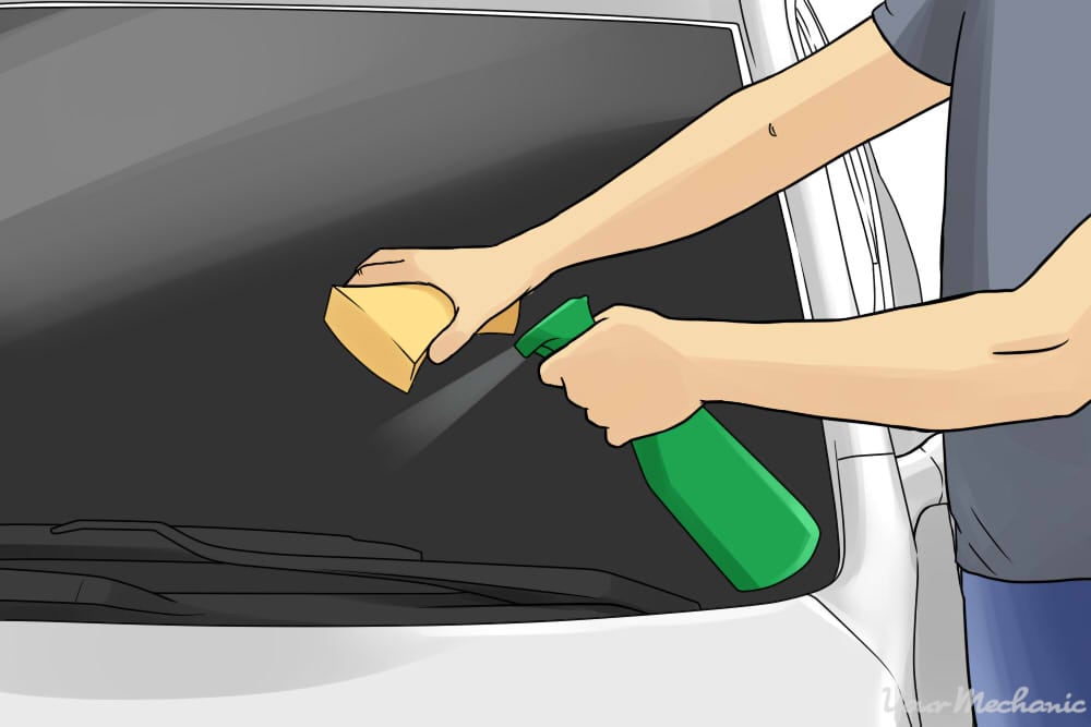 person cleaning car with sponge and spray