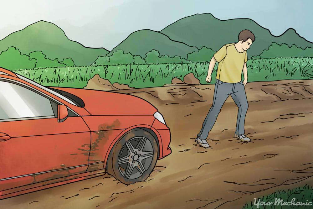 man standing outside of car, looking at mud