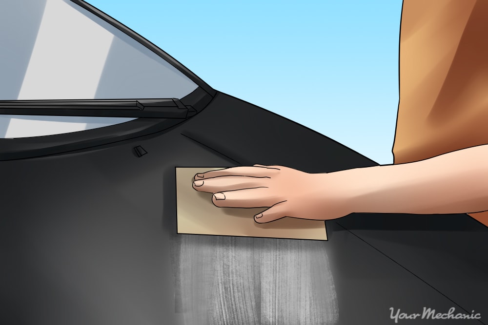 How to Properly Buff Clear Coat - A person sanding the hood of a car