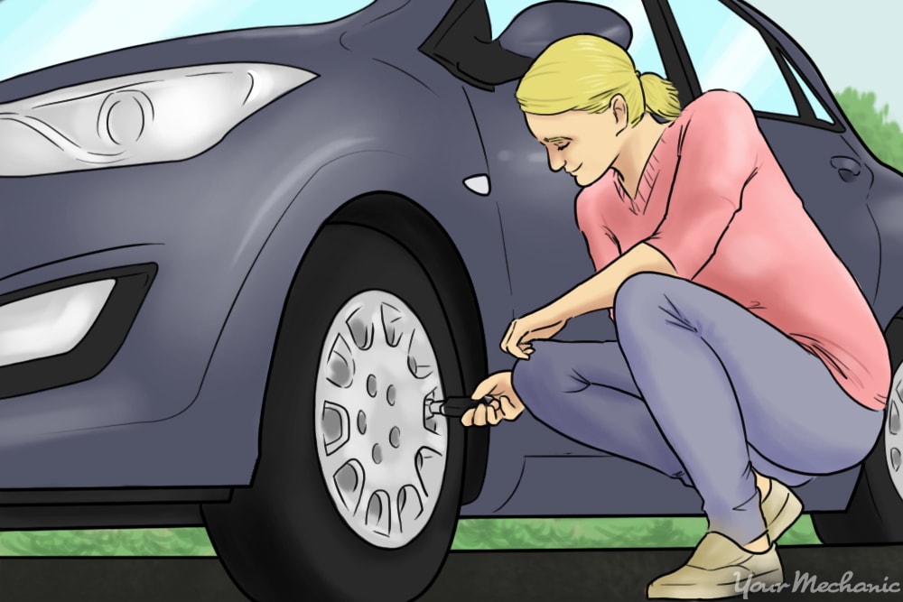 woman next to car checking tire pressure