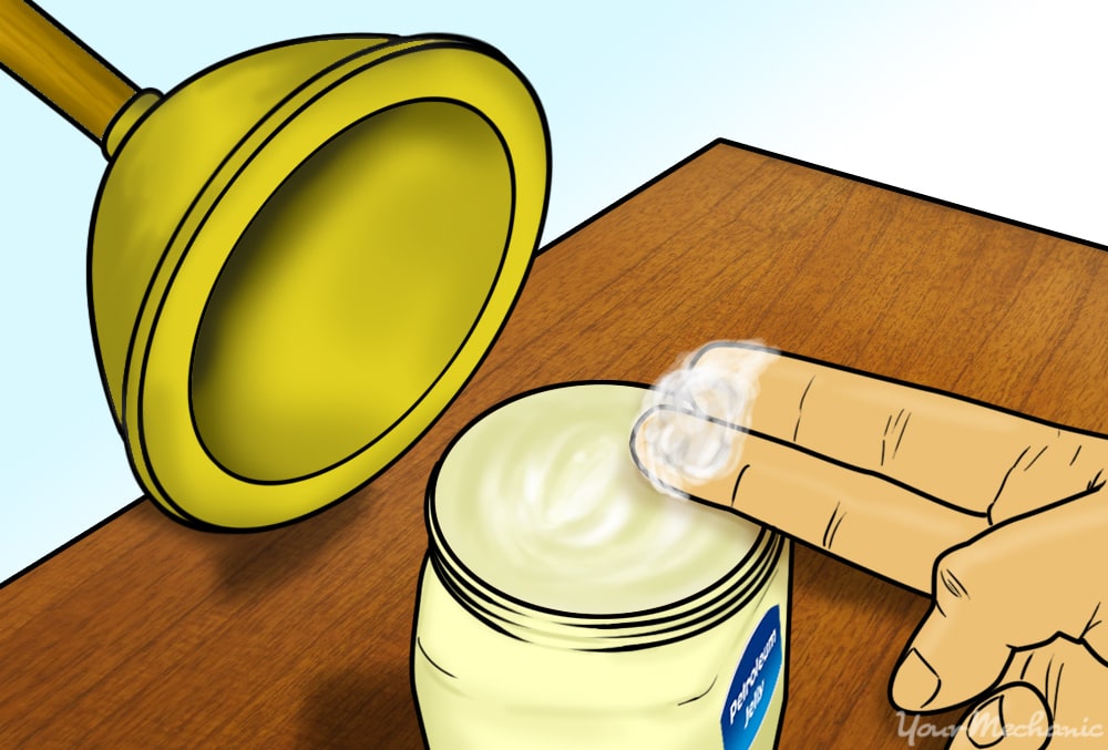 two fingers applying petroleum jelly to plunger