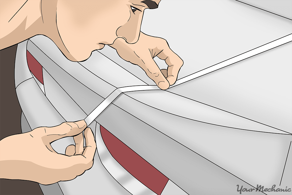 close up of man holding racing stripe up against a car