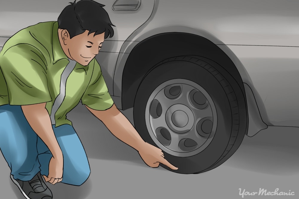 person crouched down inspecting tires