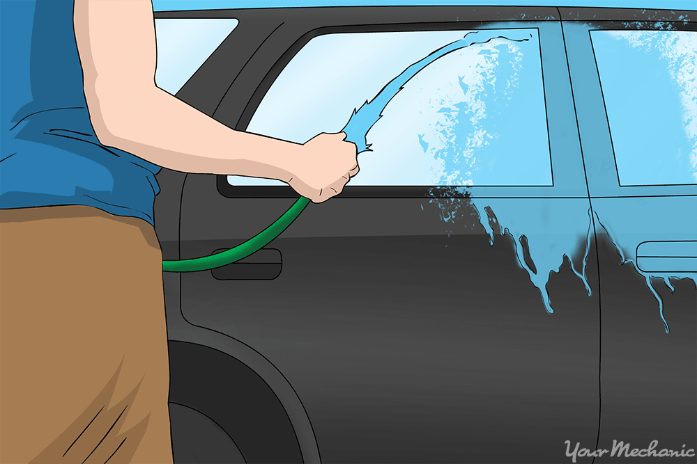 person rinsing car with hose