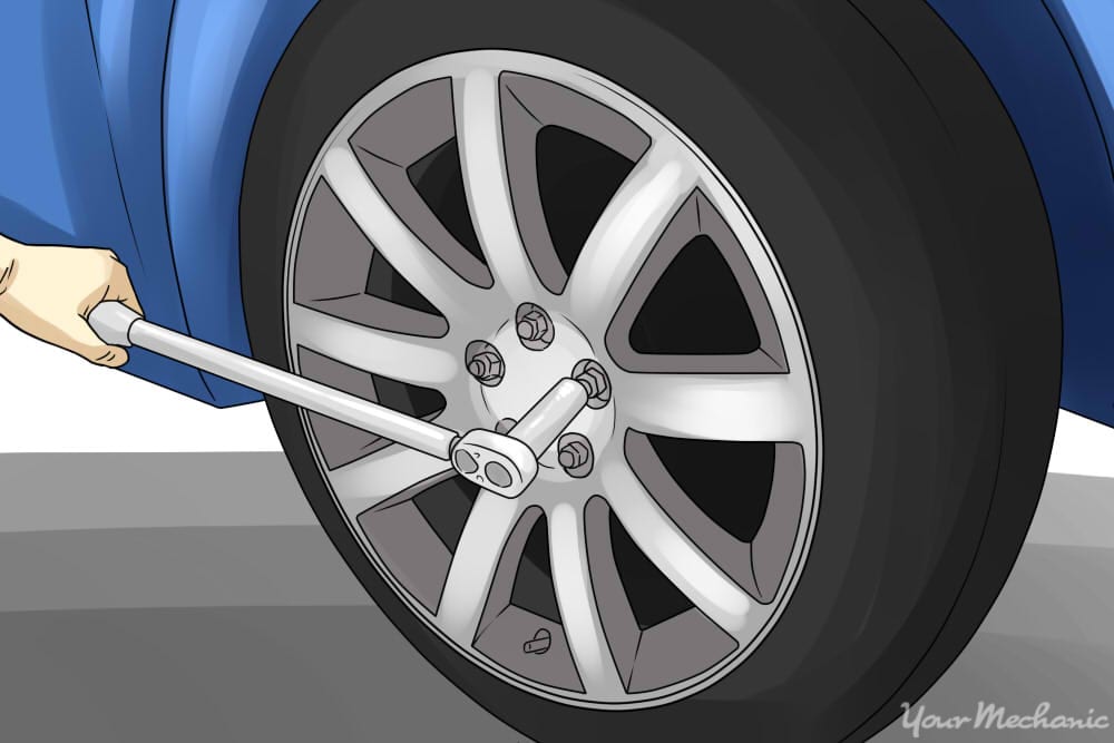 person loosening up their lug nuts on the wheel of car