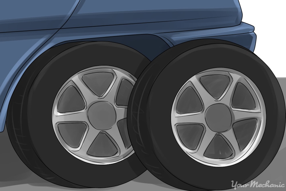 a used tire of the same size sitting next to a left rear tire already on a vehicle