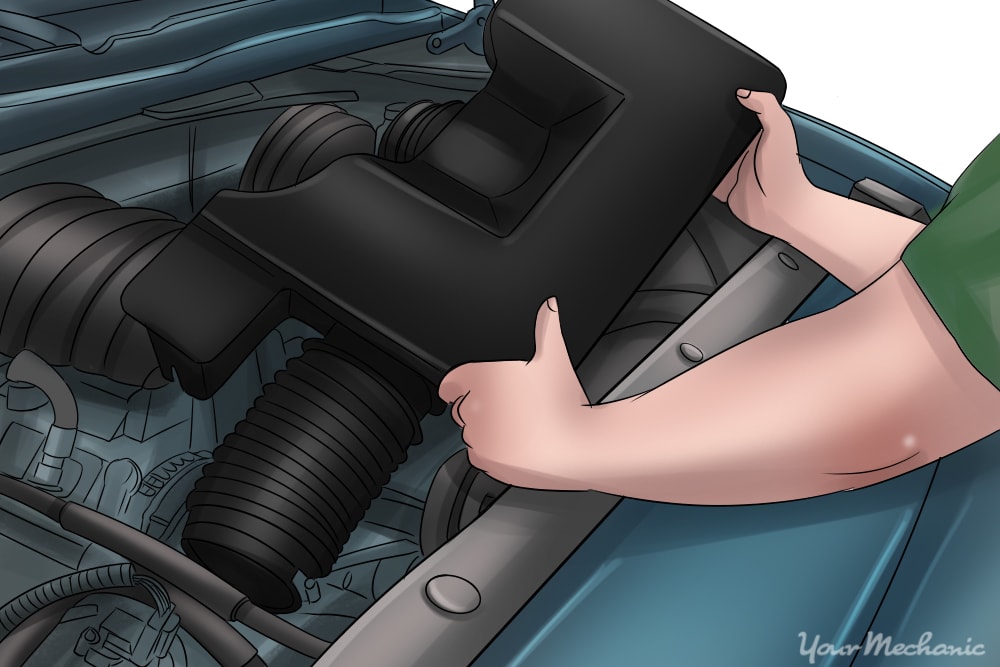 person removing air intake tube from engine