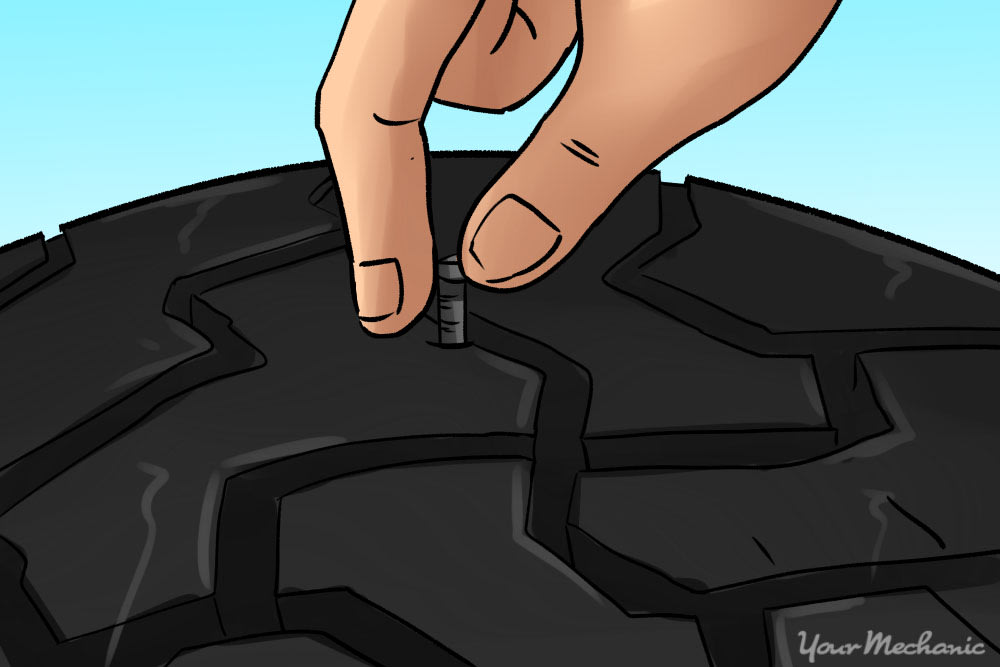 hand removing nail from tire