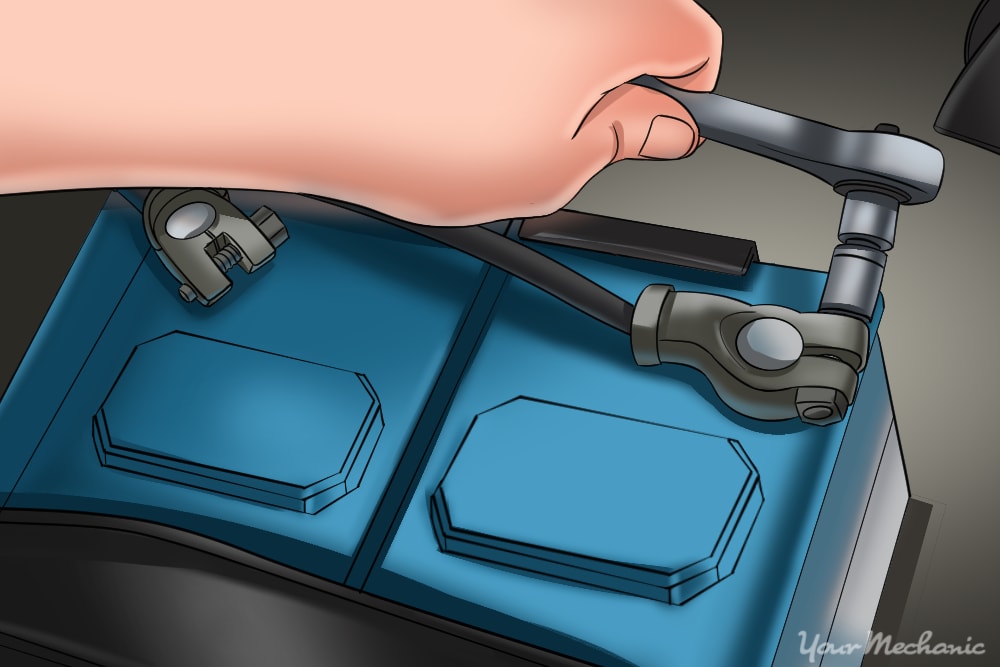 hand using a tool to disconnect a car battery cable