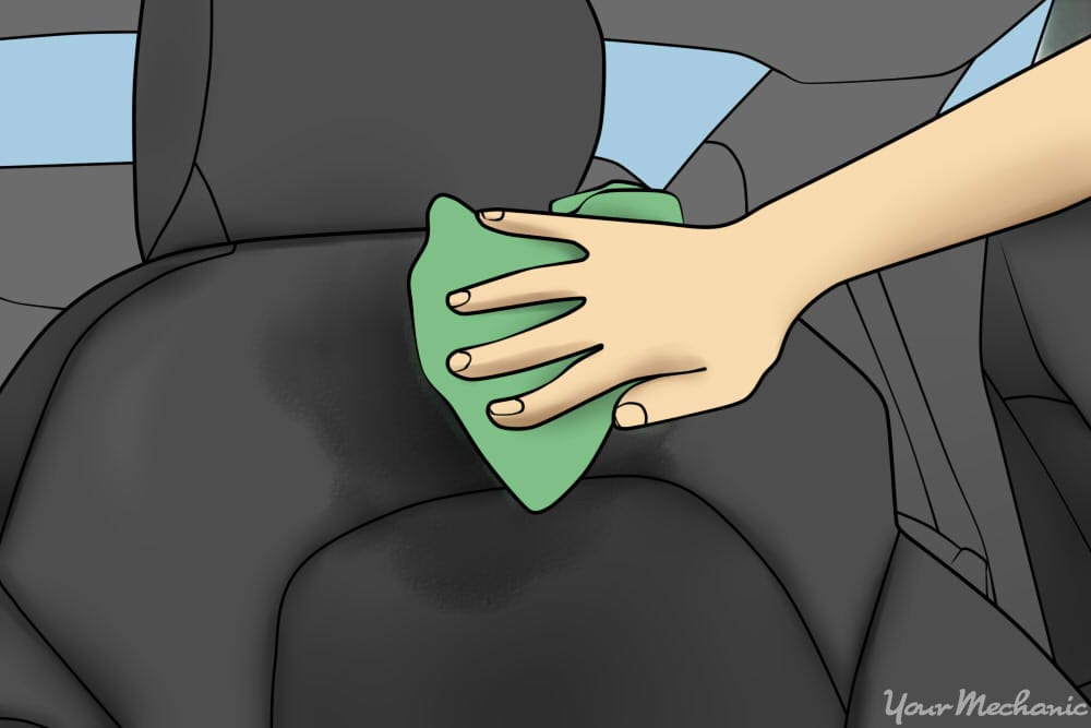 person dabbing wet spot on seat with cloth