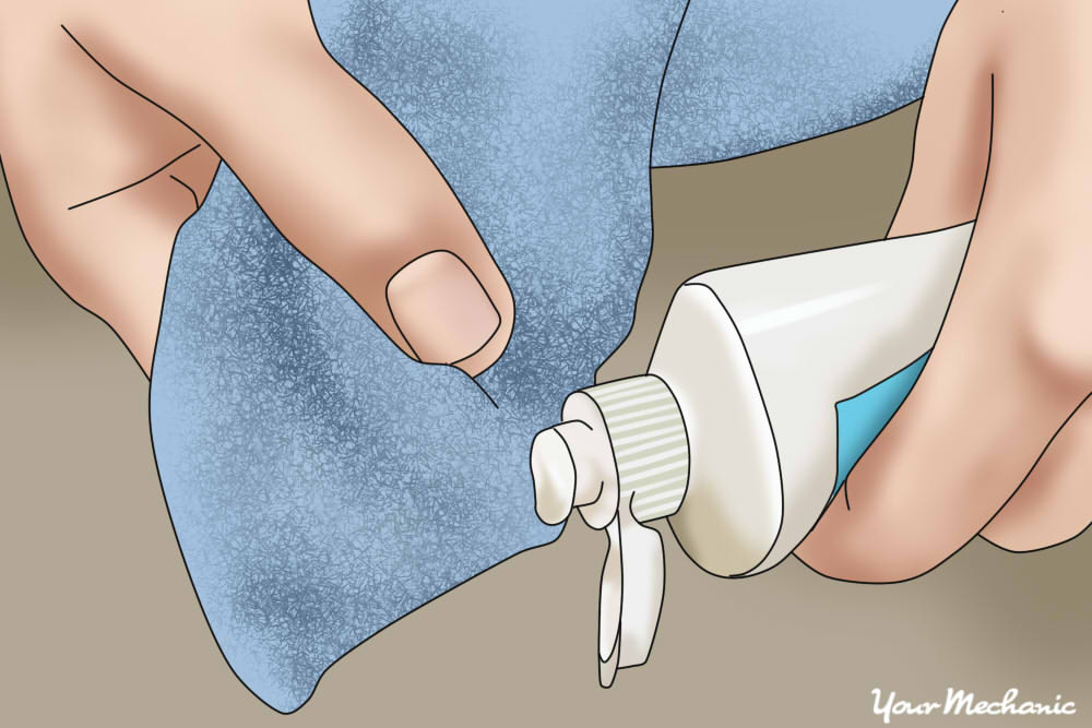 person applying toothpaste to clean cloth