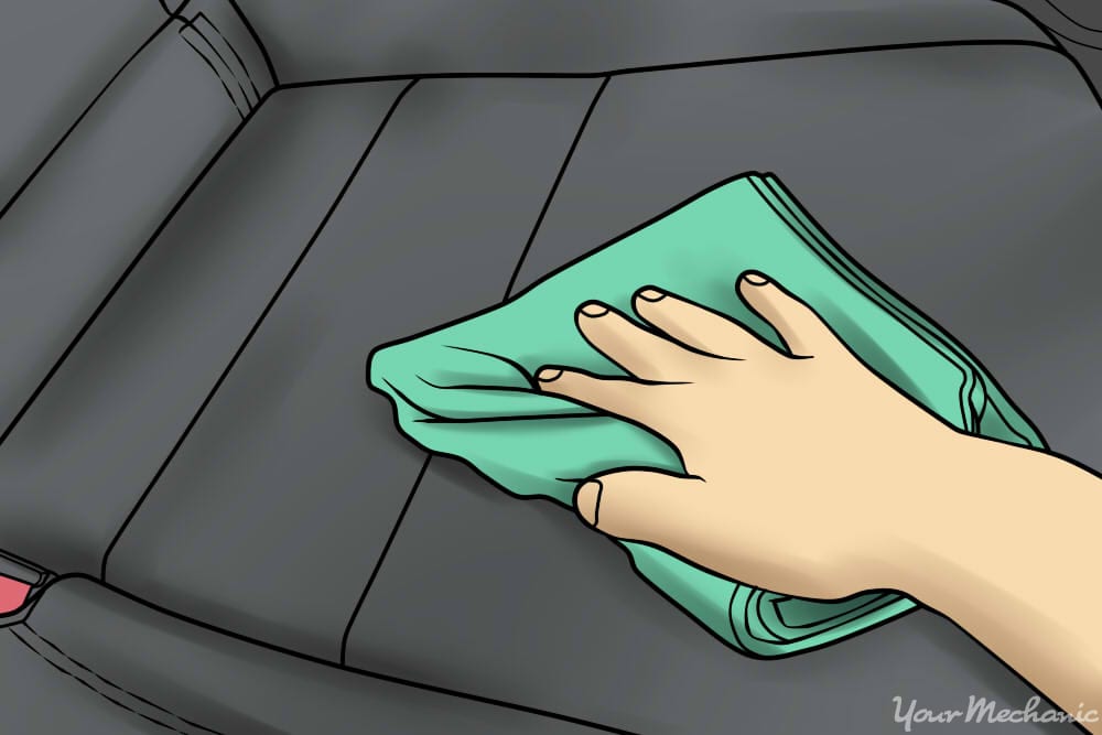 person rubbing car leather car seat with microfiber cloth