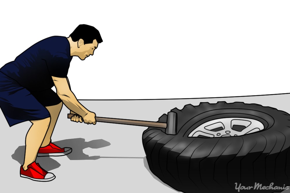 person hitting tire with sledgehammer