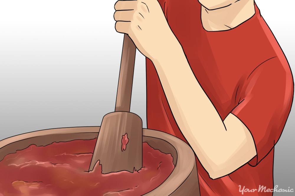 person crushing fruit with a blunt object