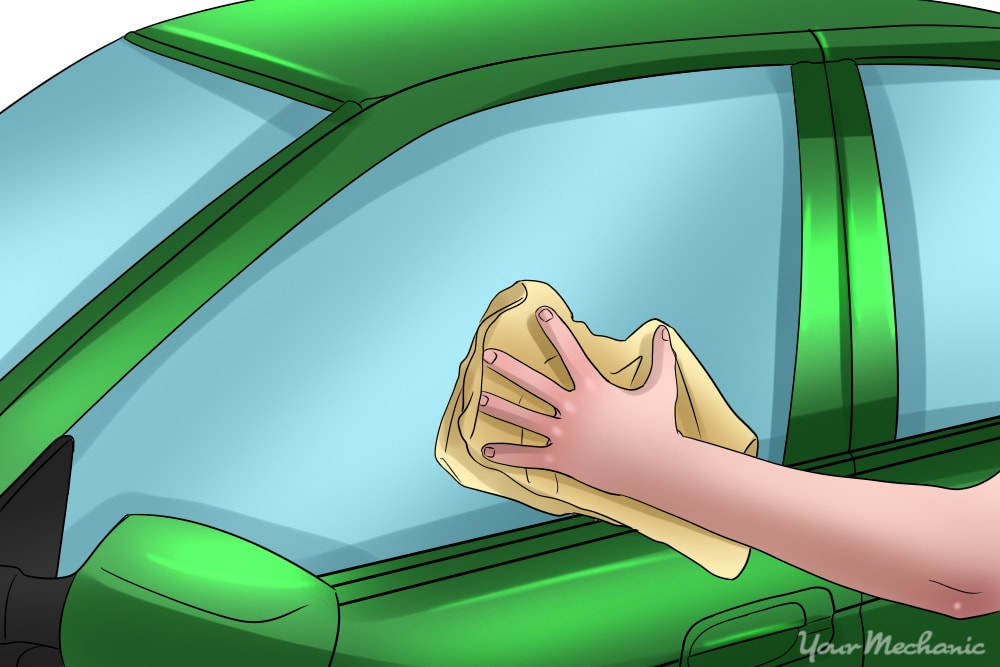 man cleaning car window with a clean cloth