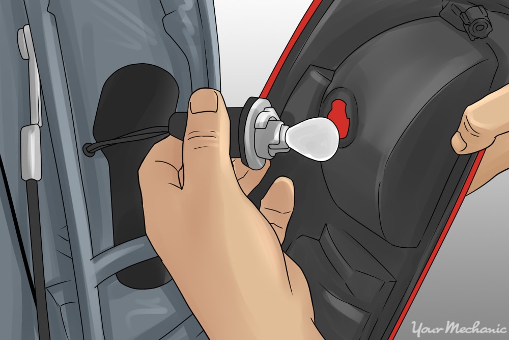 person removing a rear turn signal bulb